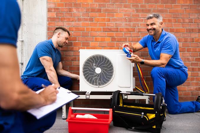 HVAC technicians working together beside an outdoor cooling unit